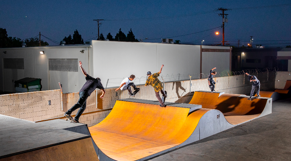 Skateboarders performing tricks at a skate park with ramps and concrete surfaces.
