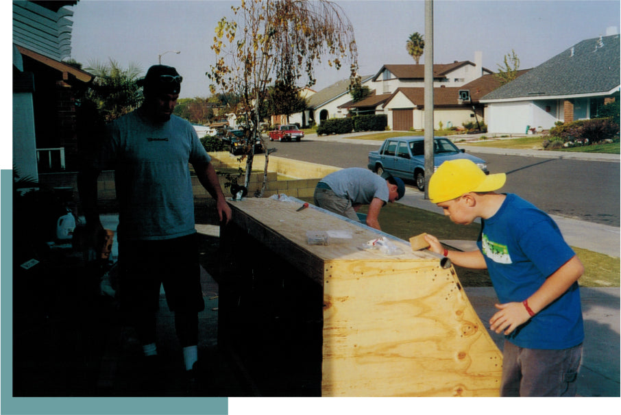 Skaters working on an early wooden ramp outside a family garage