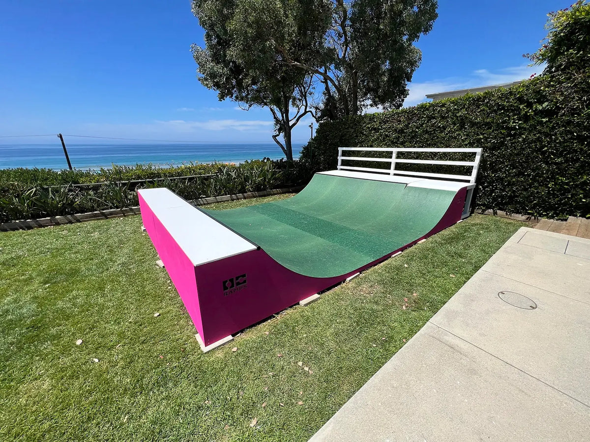 Completed backyard mini ramp with a green curved riding surface and bright pink side walls, in Silicon Valley, California.