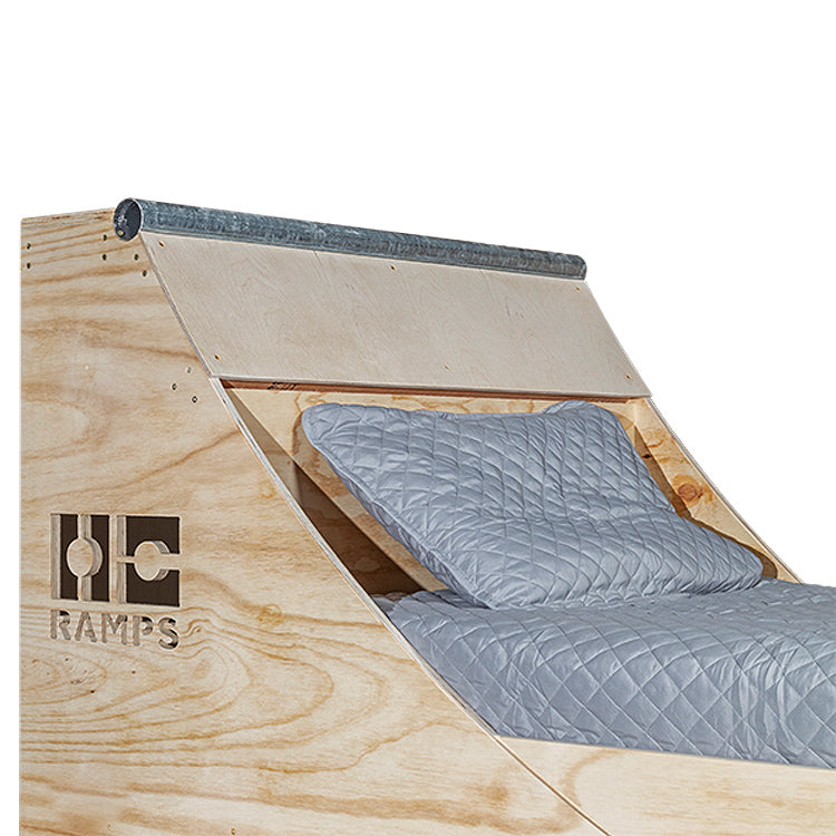 Close view of the Quarter Pipe Bed headboard with metal coping and pillows