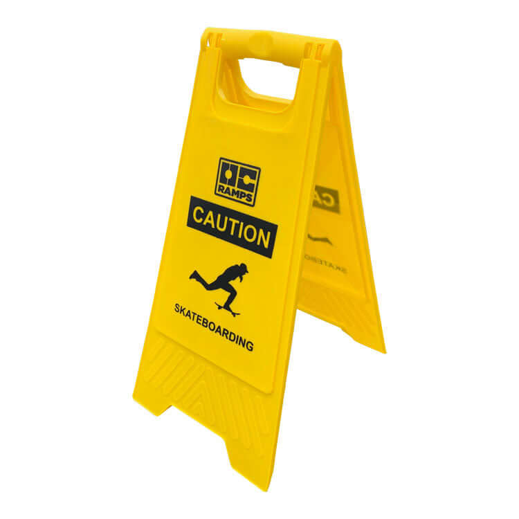 Angled view of the yellow OC Ramps Caution Skateboarding sign and carry handle
